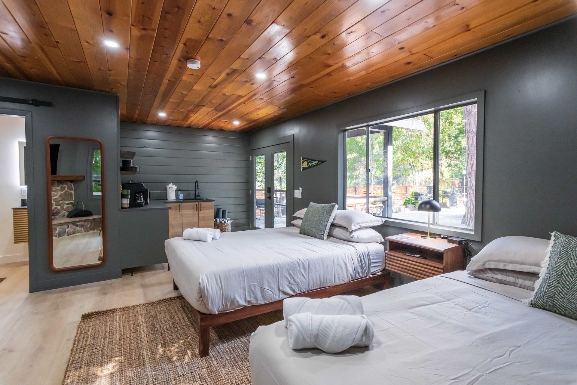 There are two beds in the room with a wooden ceiling.