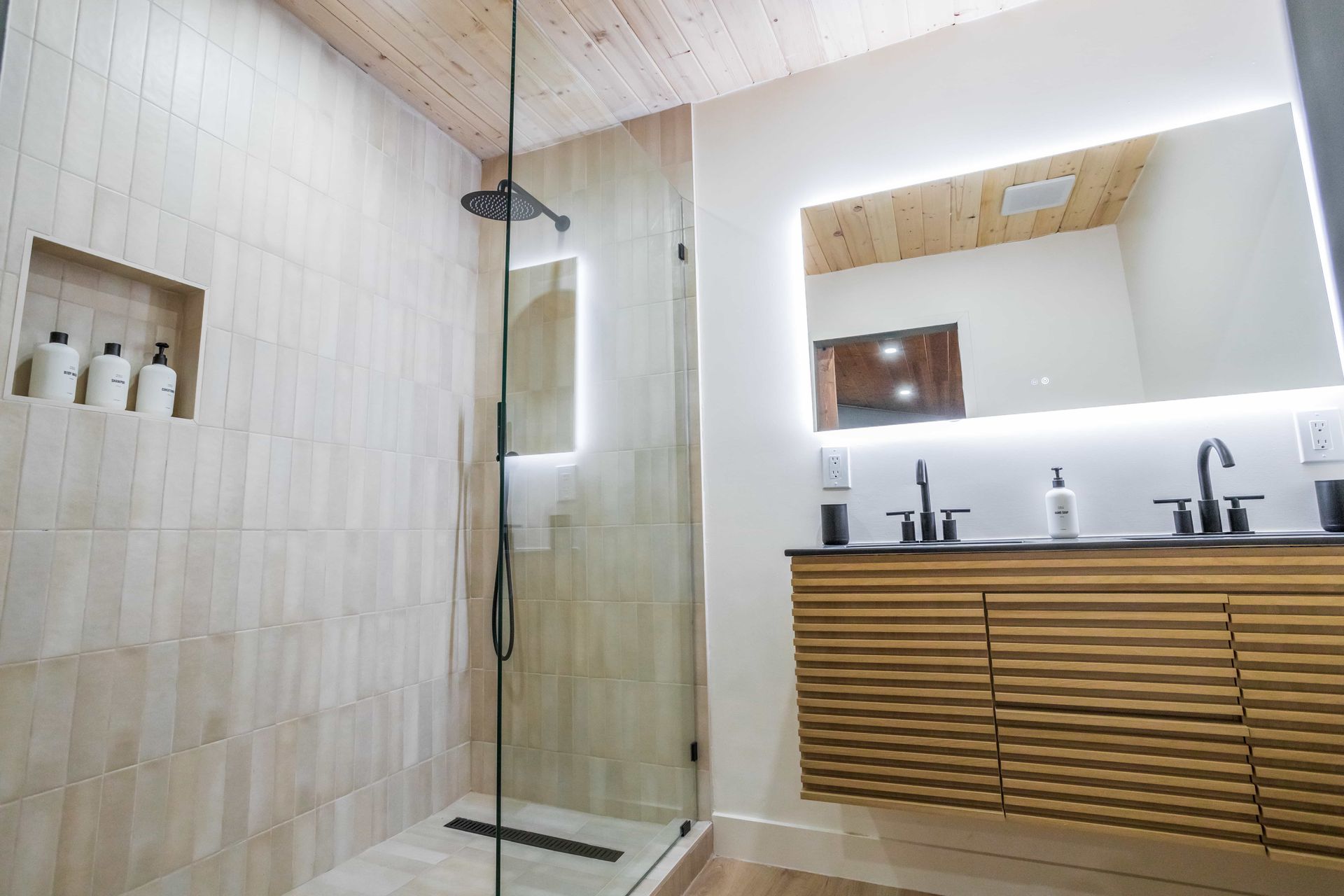 A bathroom with a walk in shower , sink and mirror.