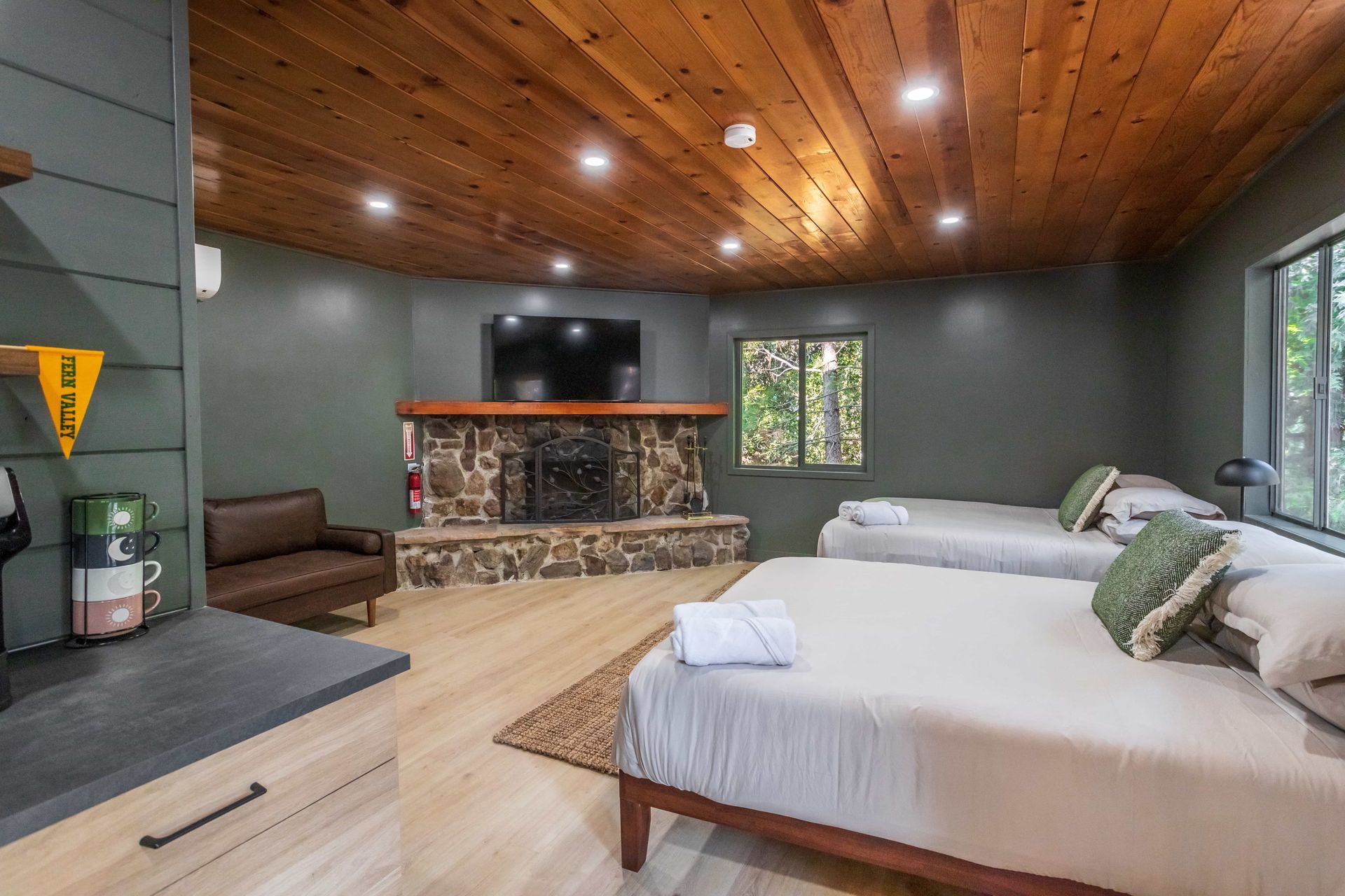 A bedroom with two beds , a fireplace and a flat screen tv.