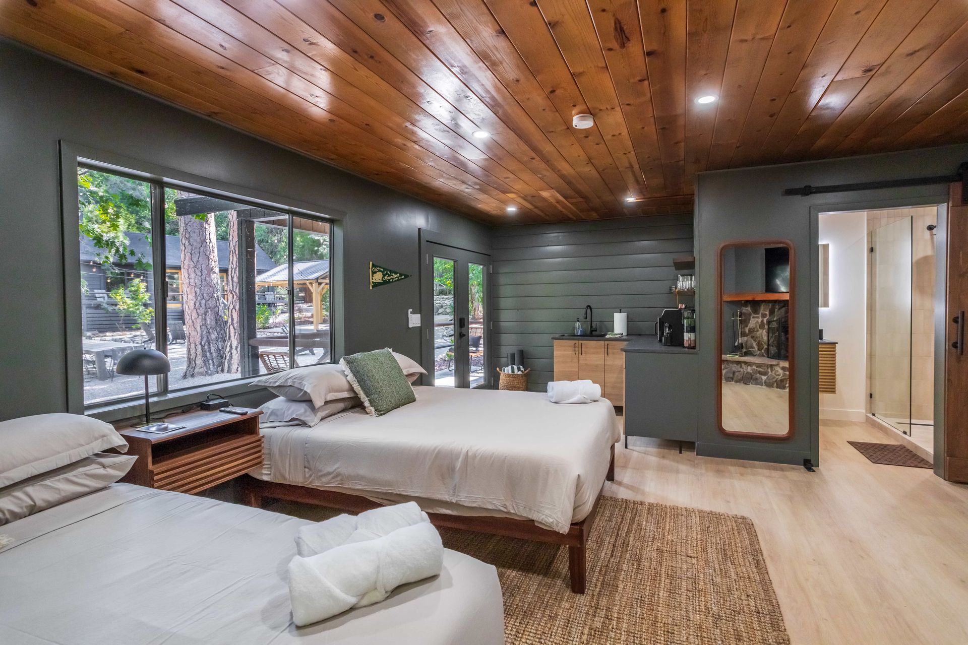 There are two beds in the room with a wooden ceiling.