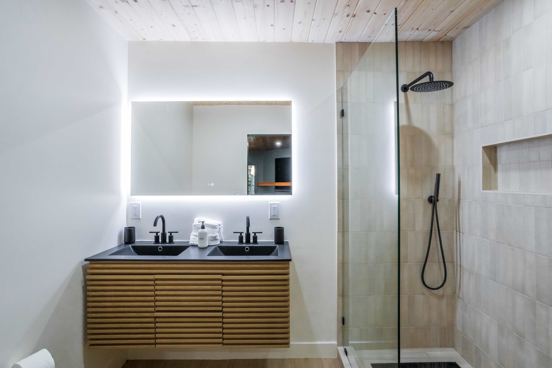 A bathroom with two sinks and a walk in shower.