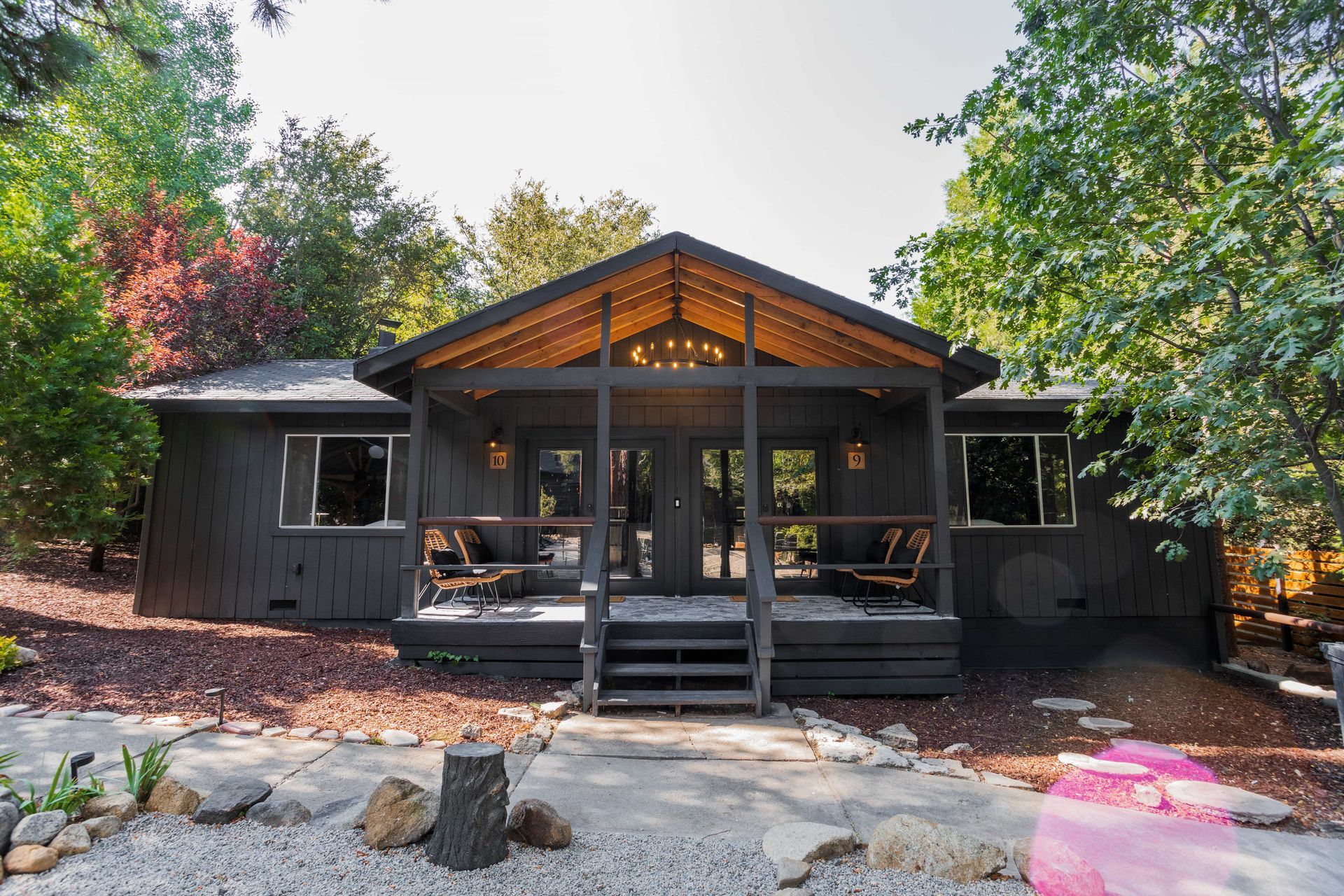 A black house with a porch and trees in the background.