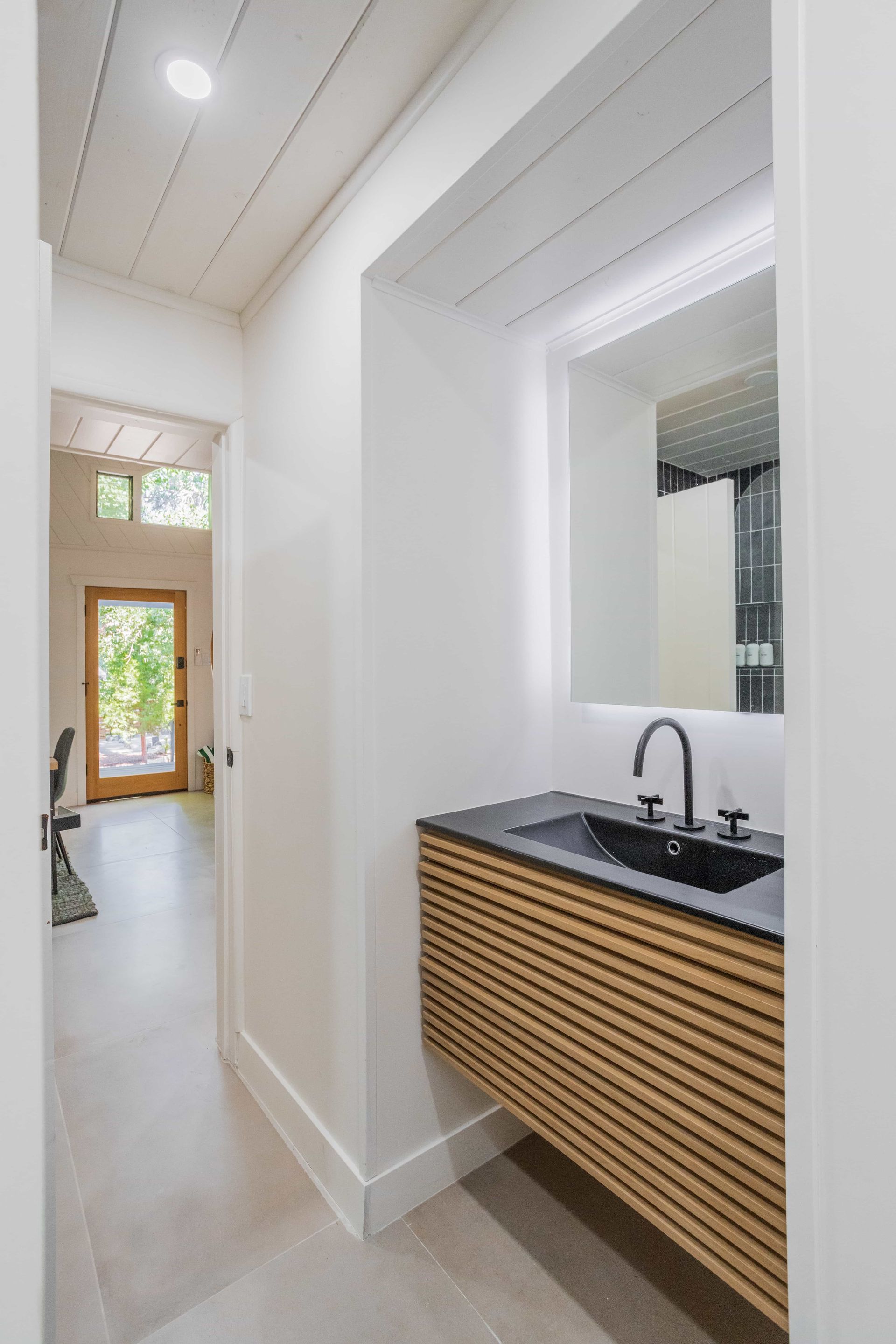 A bathroom with a sink , mirror and wooden cabinets.