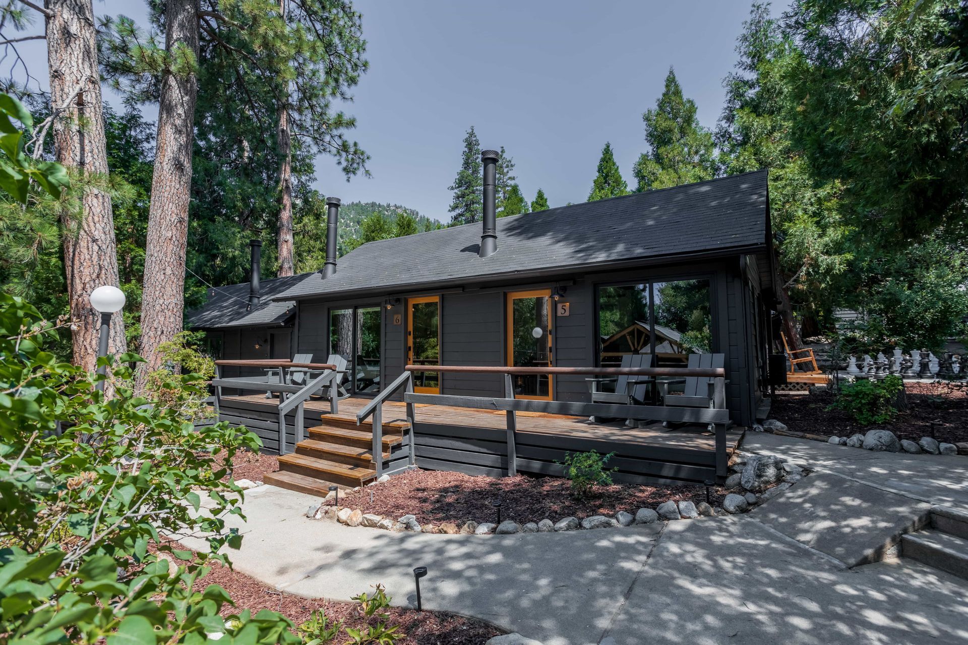 A small house with a large deck in the middle of a forest.