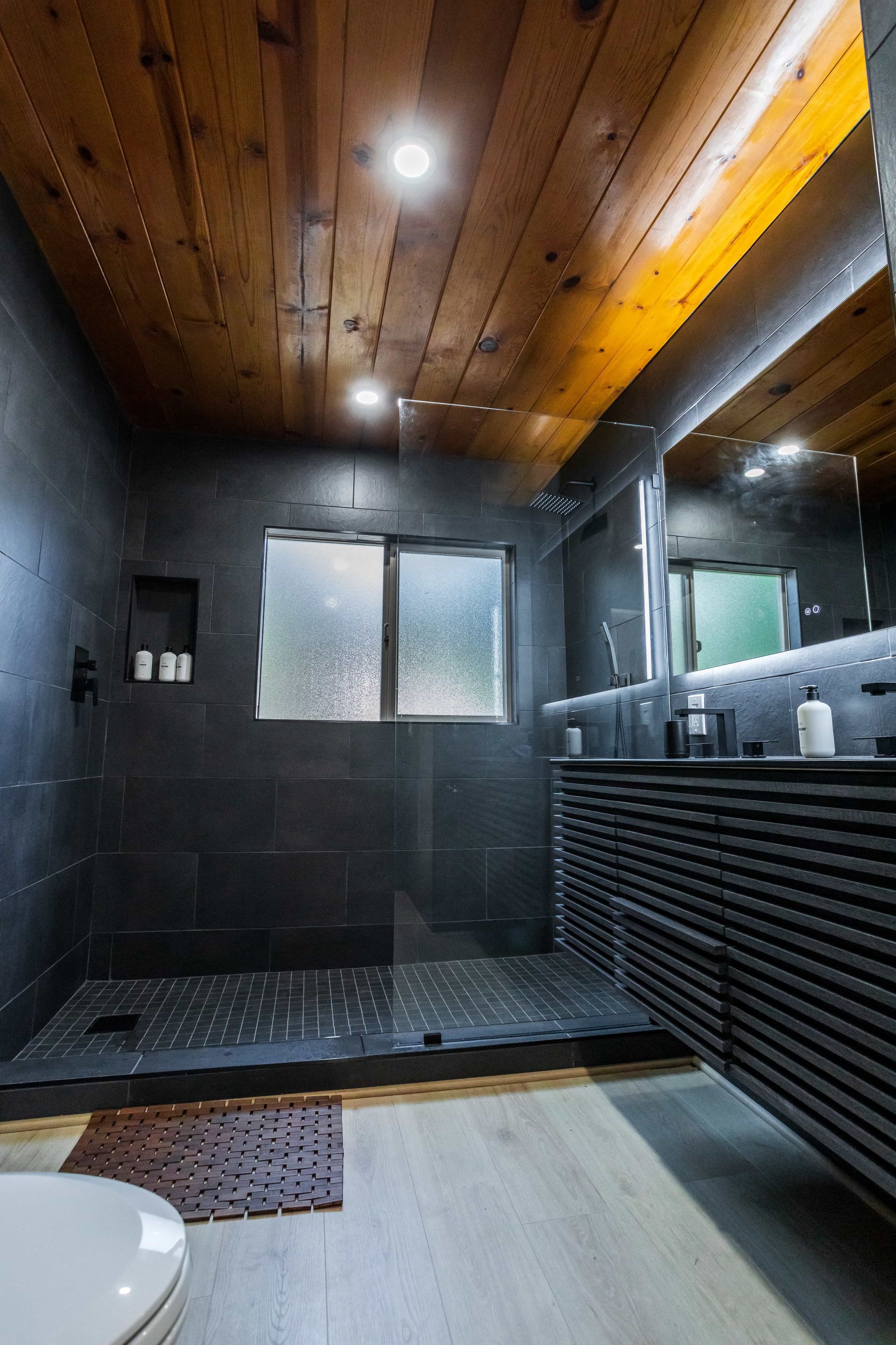 A bathroom with a toilet , sink , shower and mirror.