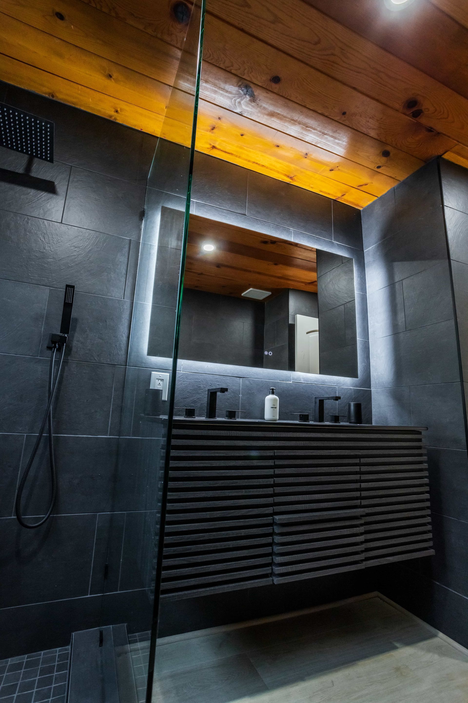 A bathroom with a sink , mirror and shower.