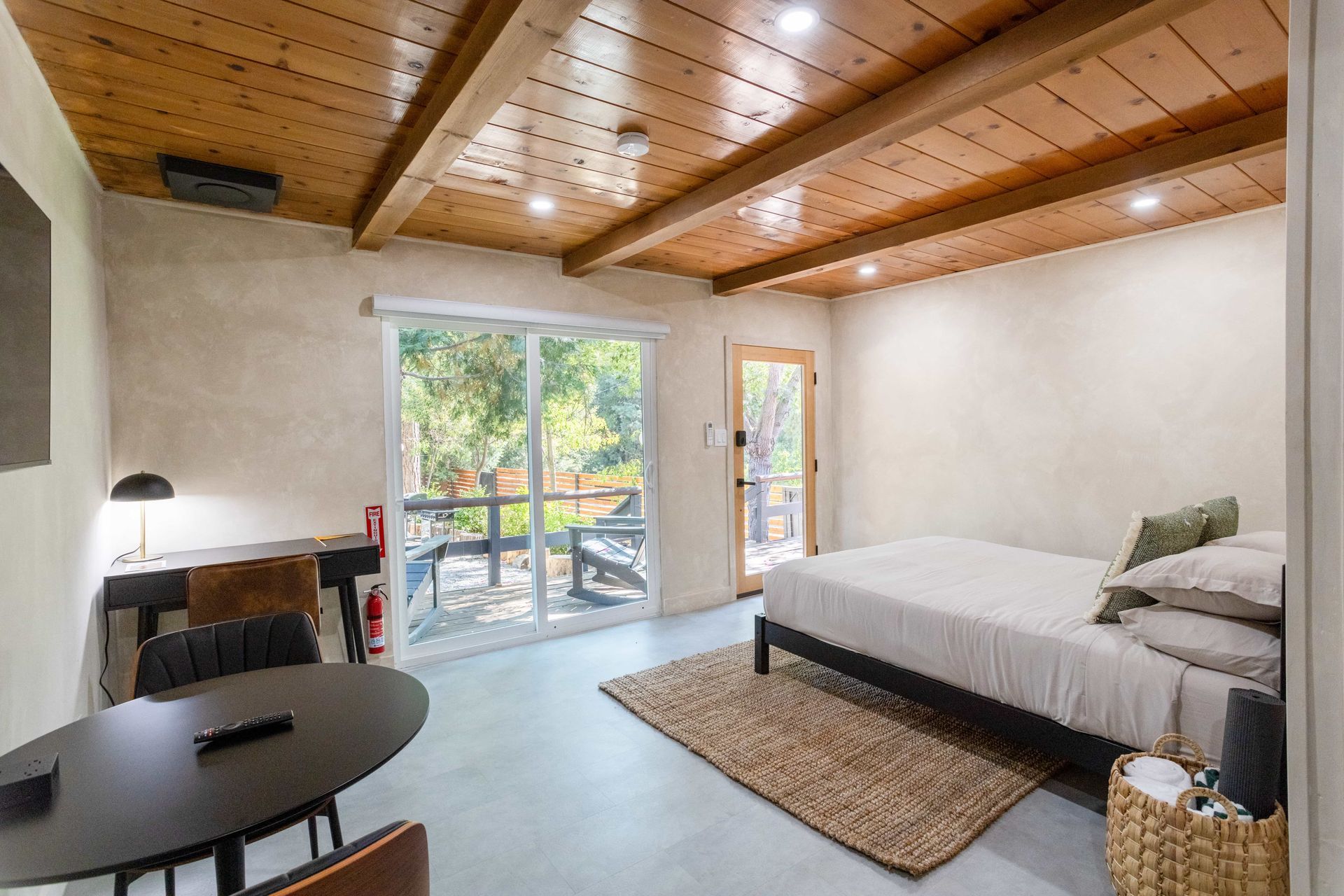 A bedroom with a bed , table , chairs and a sliding glass door.