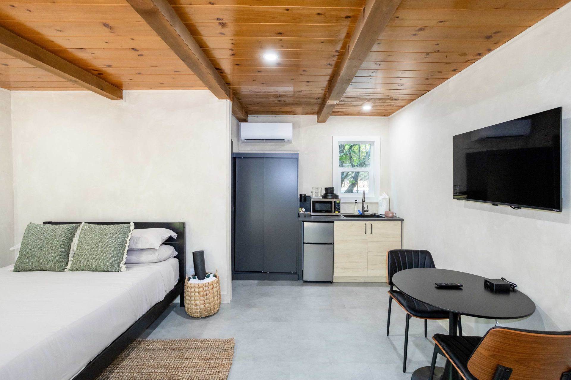 A bedroom with a bed , table , chairs and a flat screen tv.