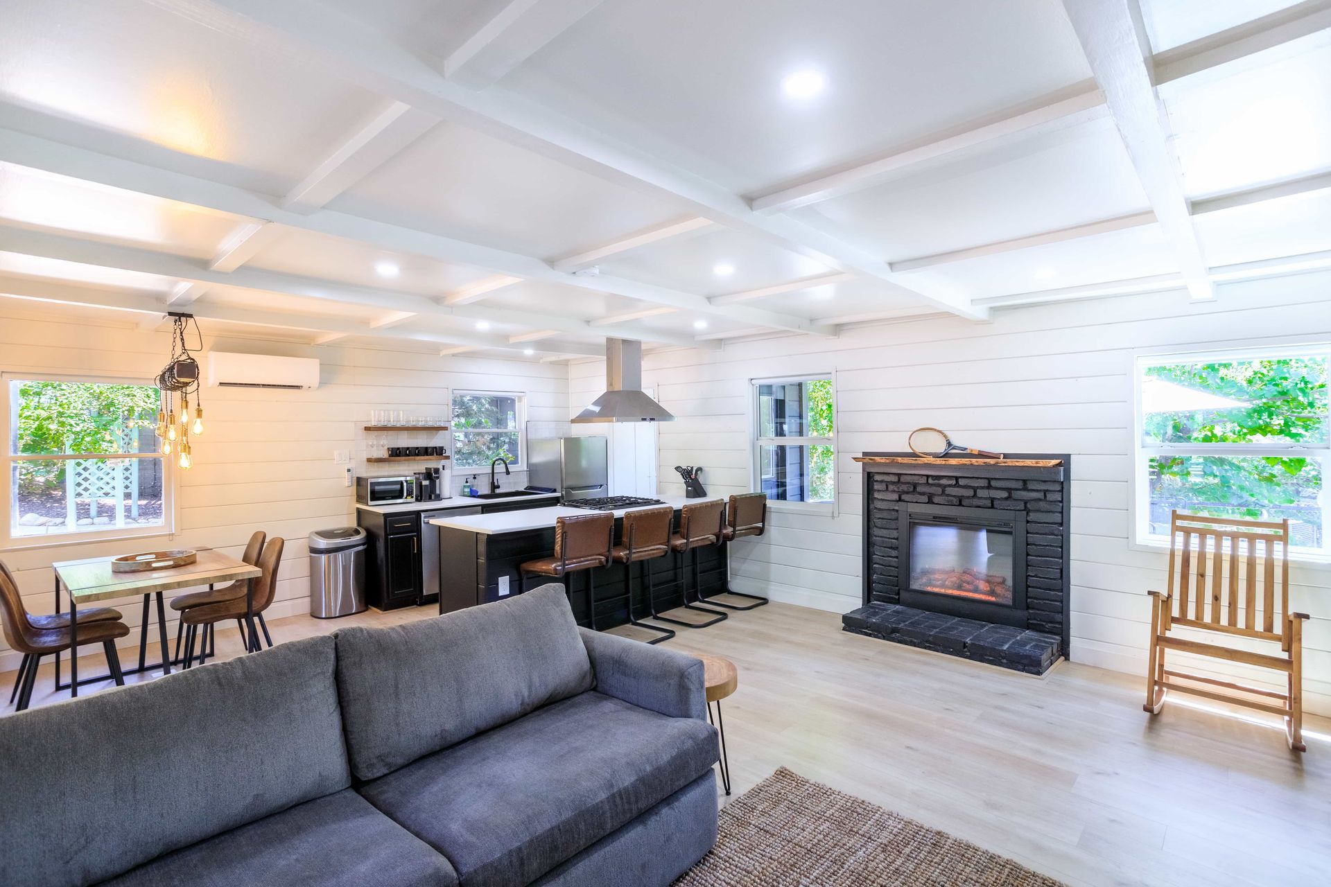 A living room with a couch , fireplace , table and chairs.