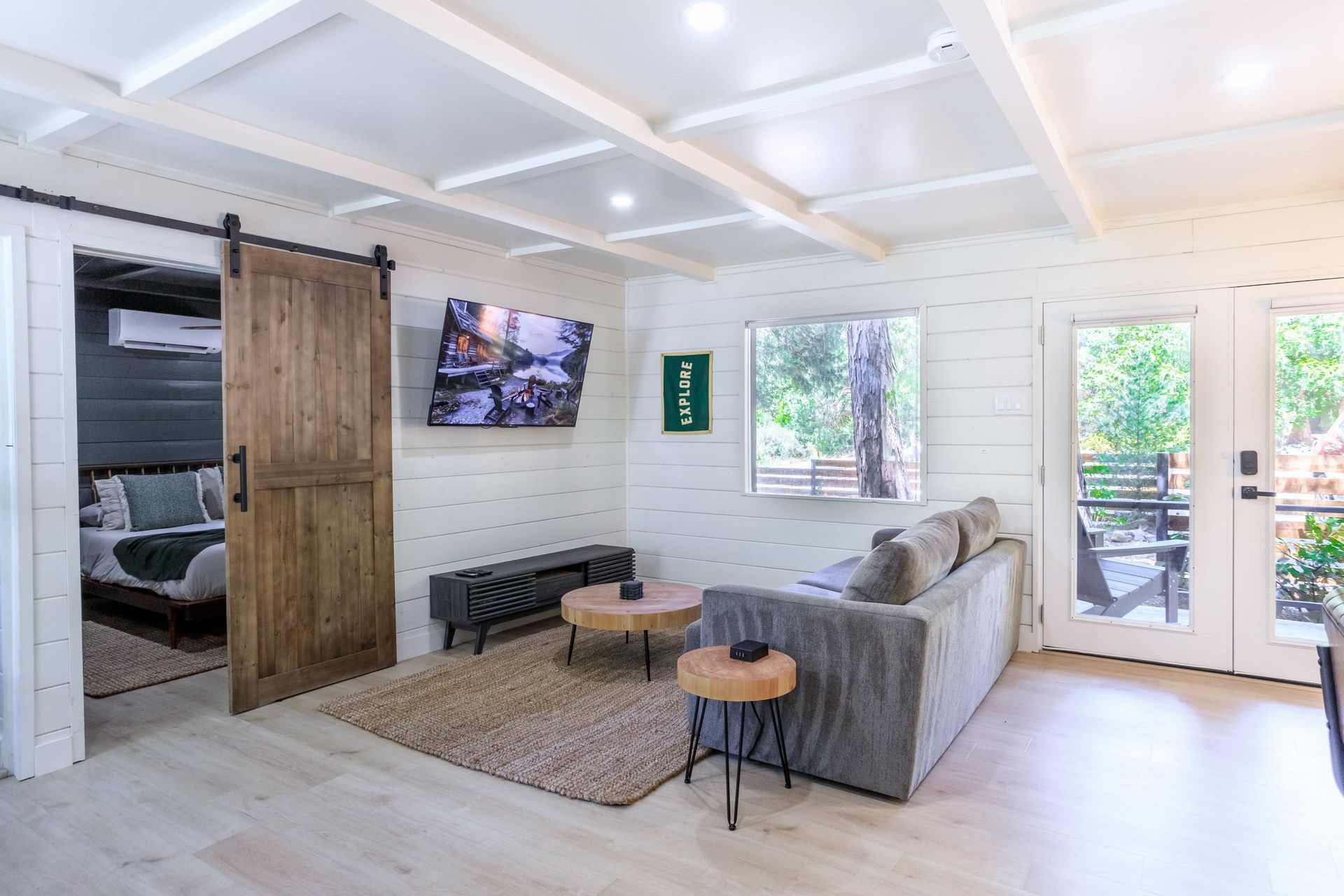 A living room with a couch , tables , a television and a sliding barn door.