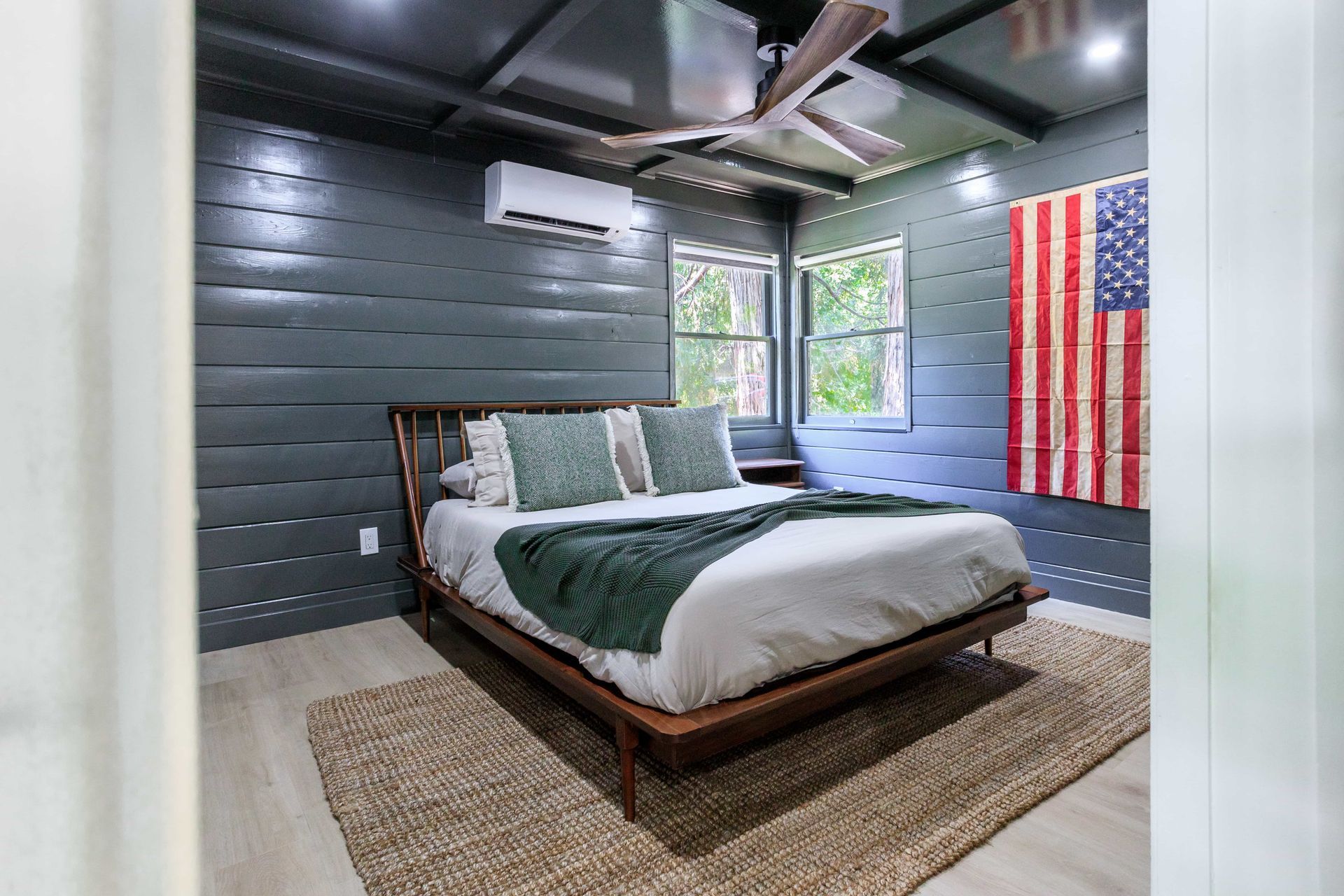 A bedroom with a bed and an american flag on the wall.