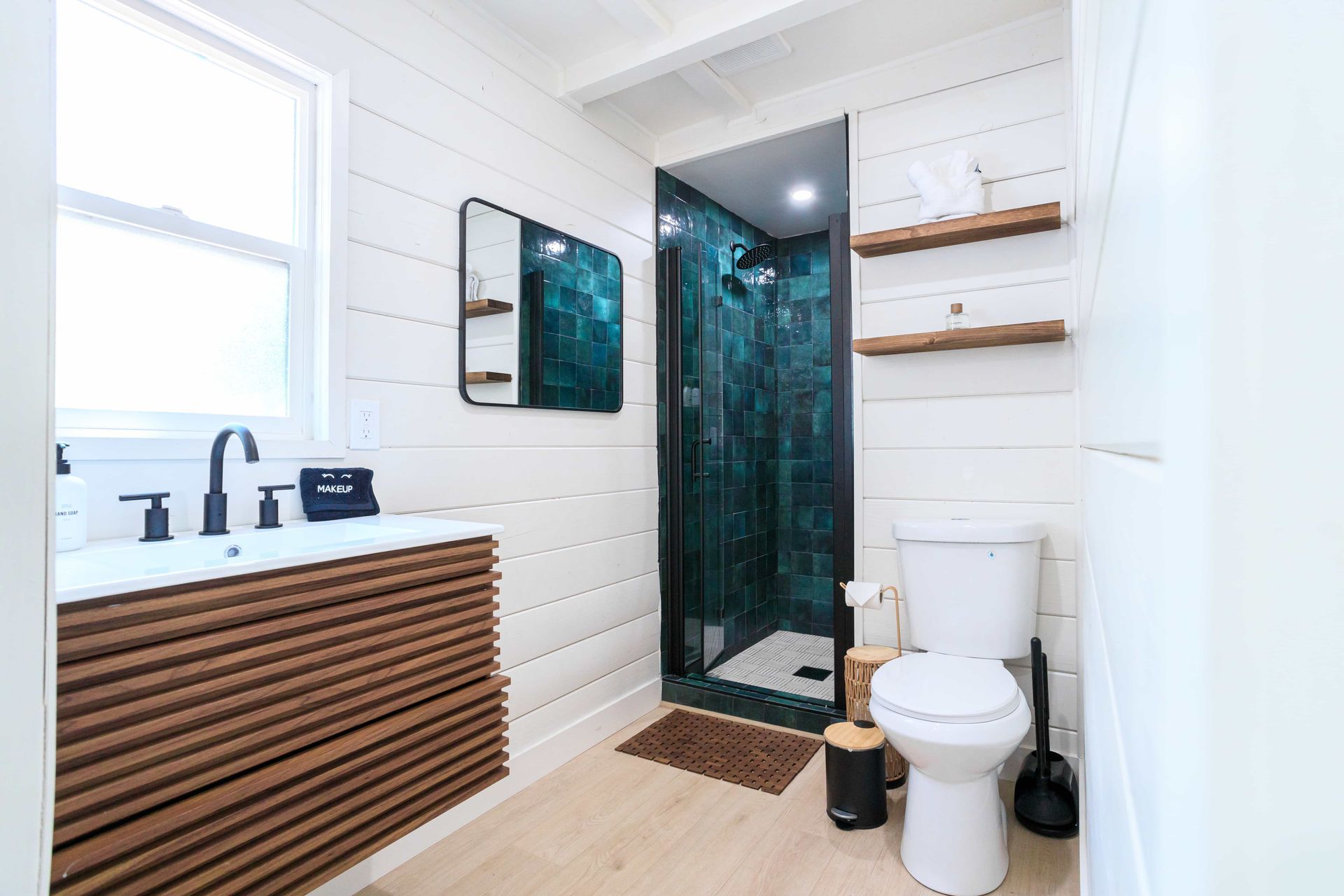 A bathroom with a toilet , sink , mirror and shower.