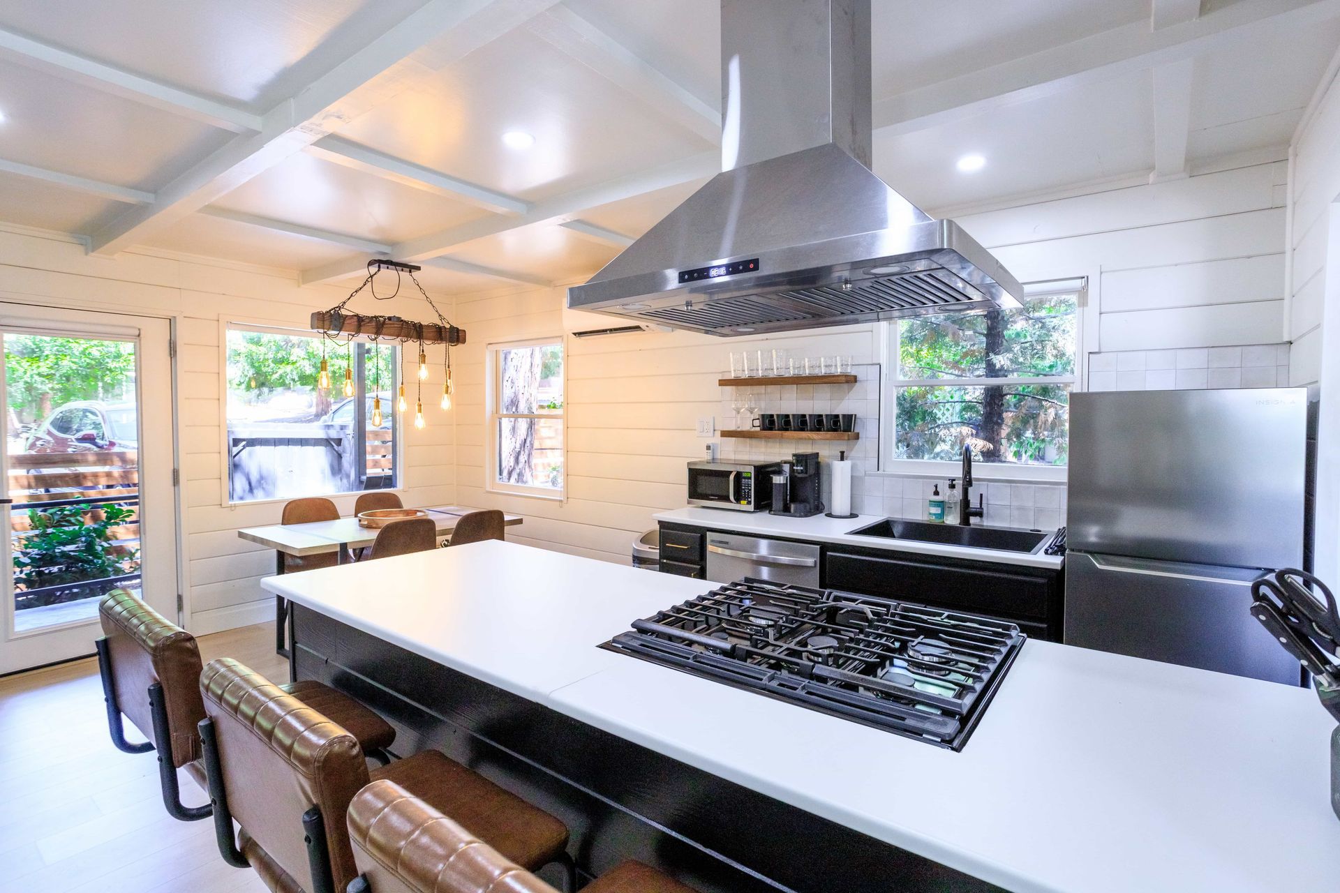 A kitchen with a large island , stove top oven , refrigerator , and stainless steel appliances.