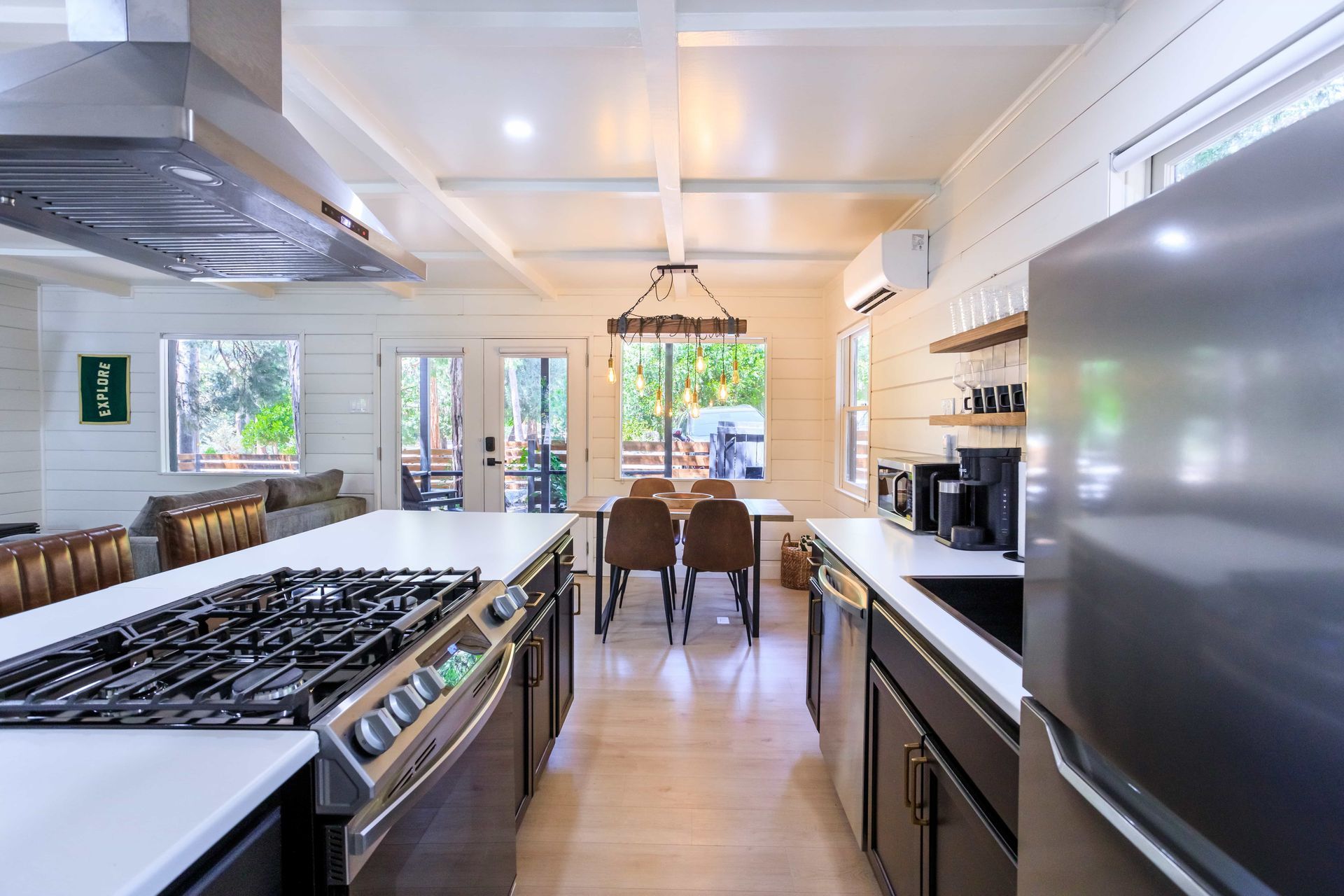 A kitchen with a stove , refrigerator , and a dining room in the background.