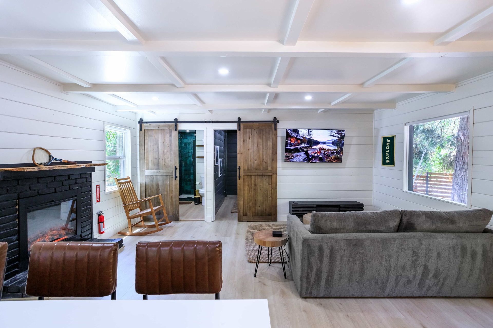 A living room with a couch , chairs , fireplace and television.