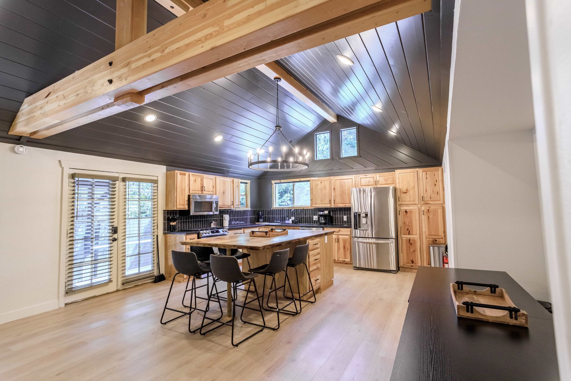 A kitchen with a large island , stainless steel appliances , wooden cabinets and a black ceiling.