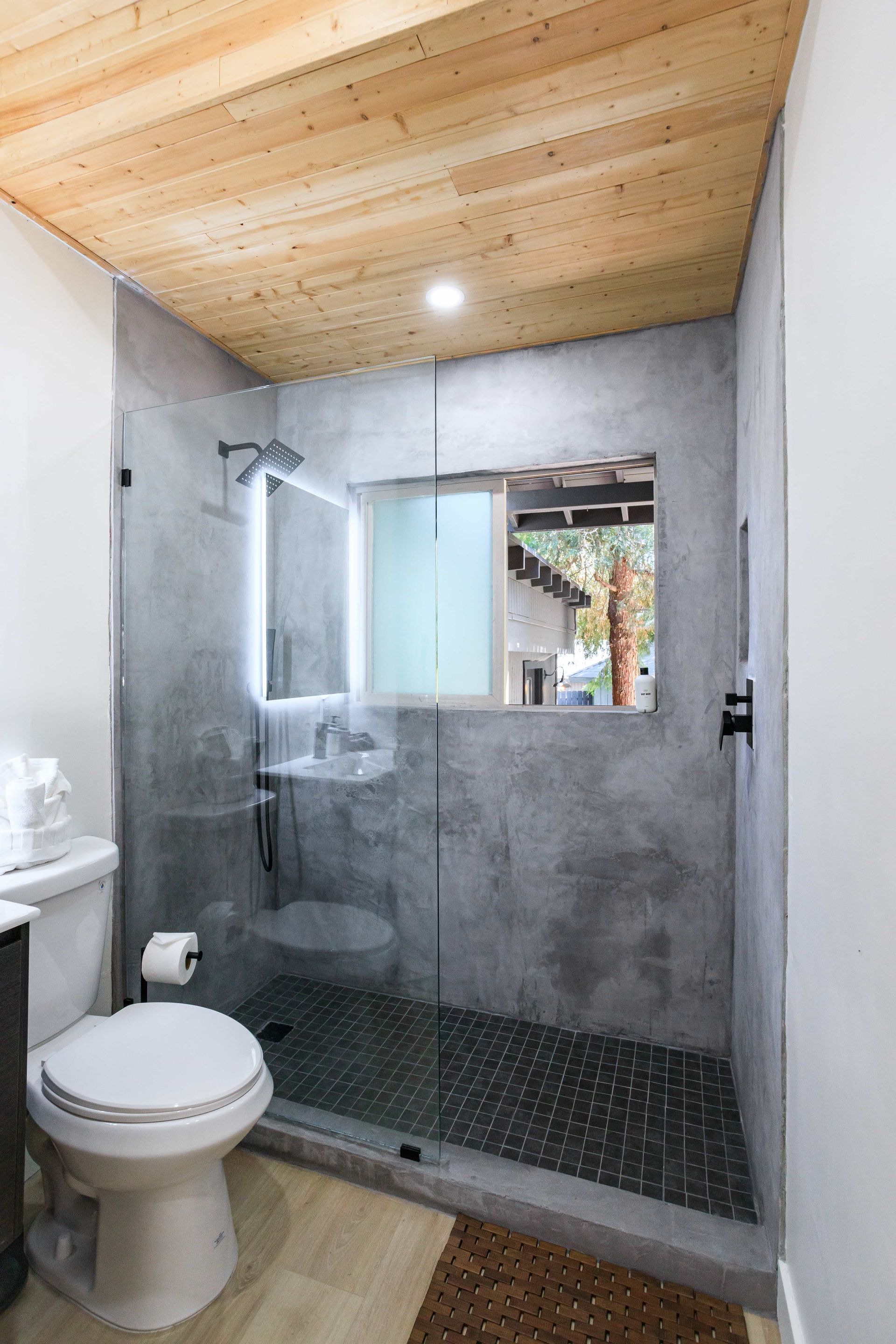 A bathroom with a toilet , sink and walk in shower.