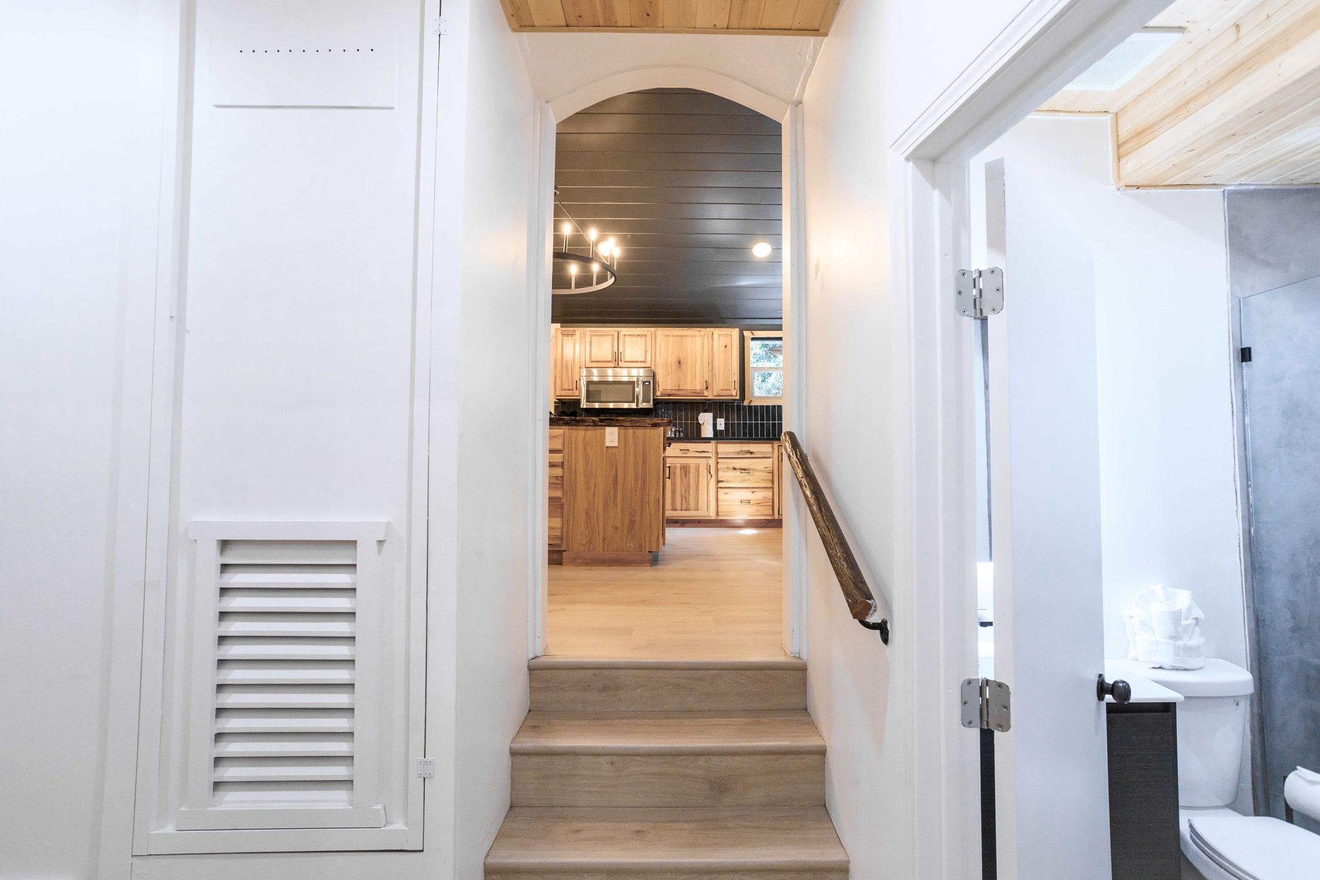 A hallway with stairs leading up to a kitchen and bathroom.