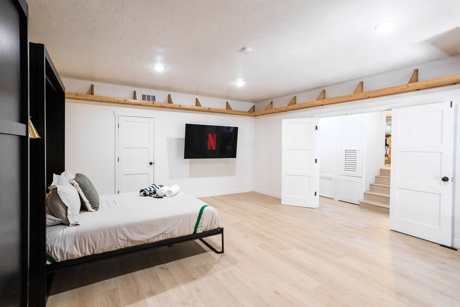 A bedroom with a large bed and a flat screen tv on the wall.