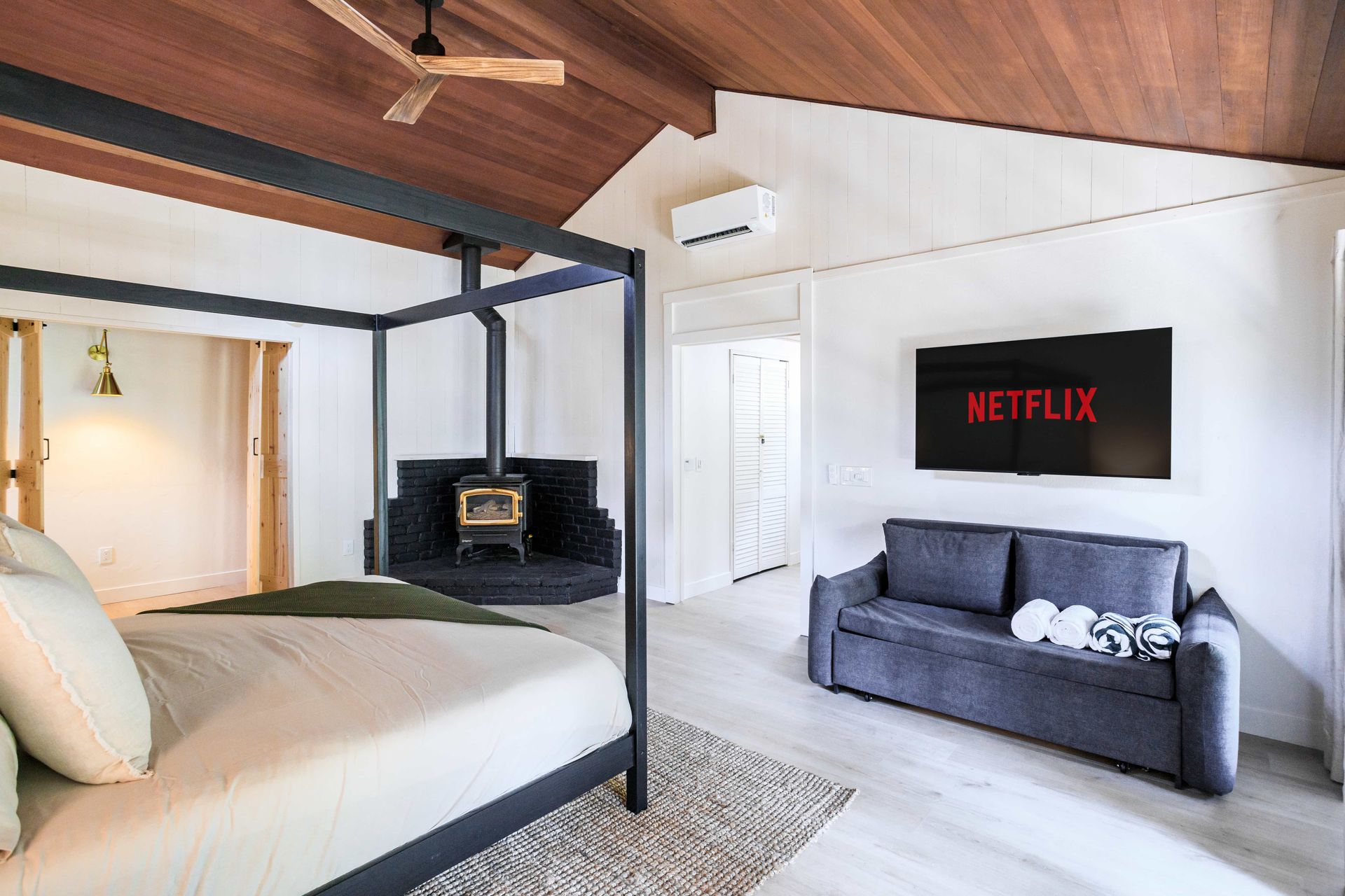 A bedroom with a canopy bed and a couch and a netflix sign on the wall.
