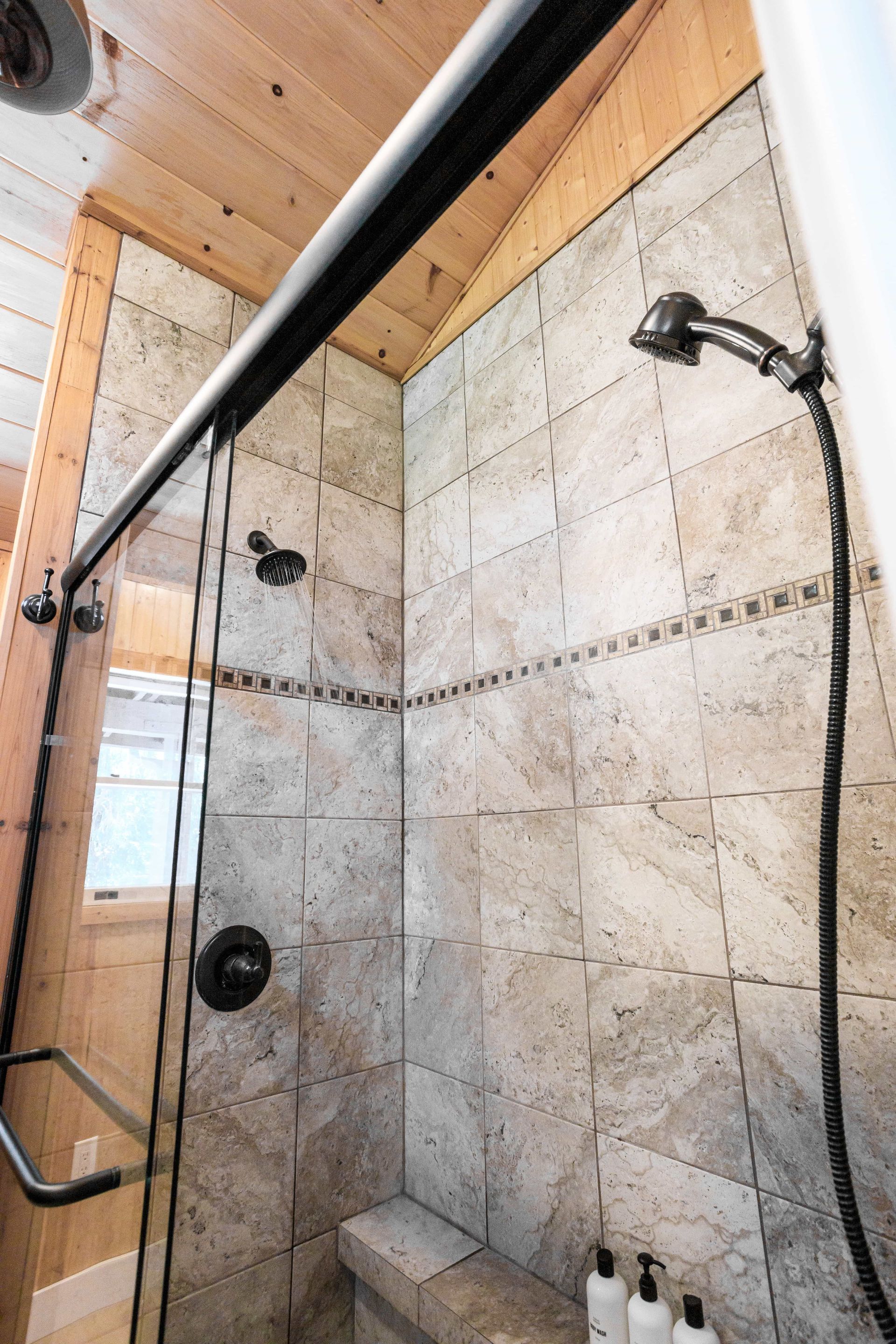 A bathroom with a sliding glass shower door and a bench.