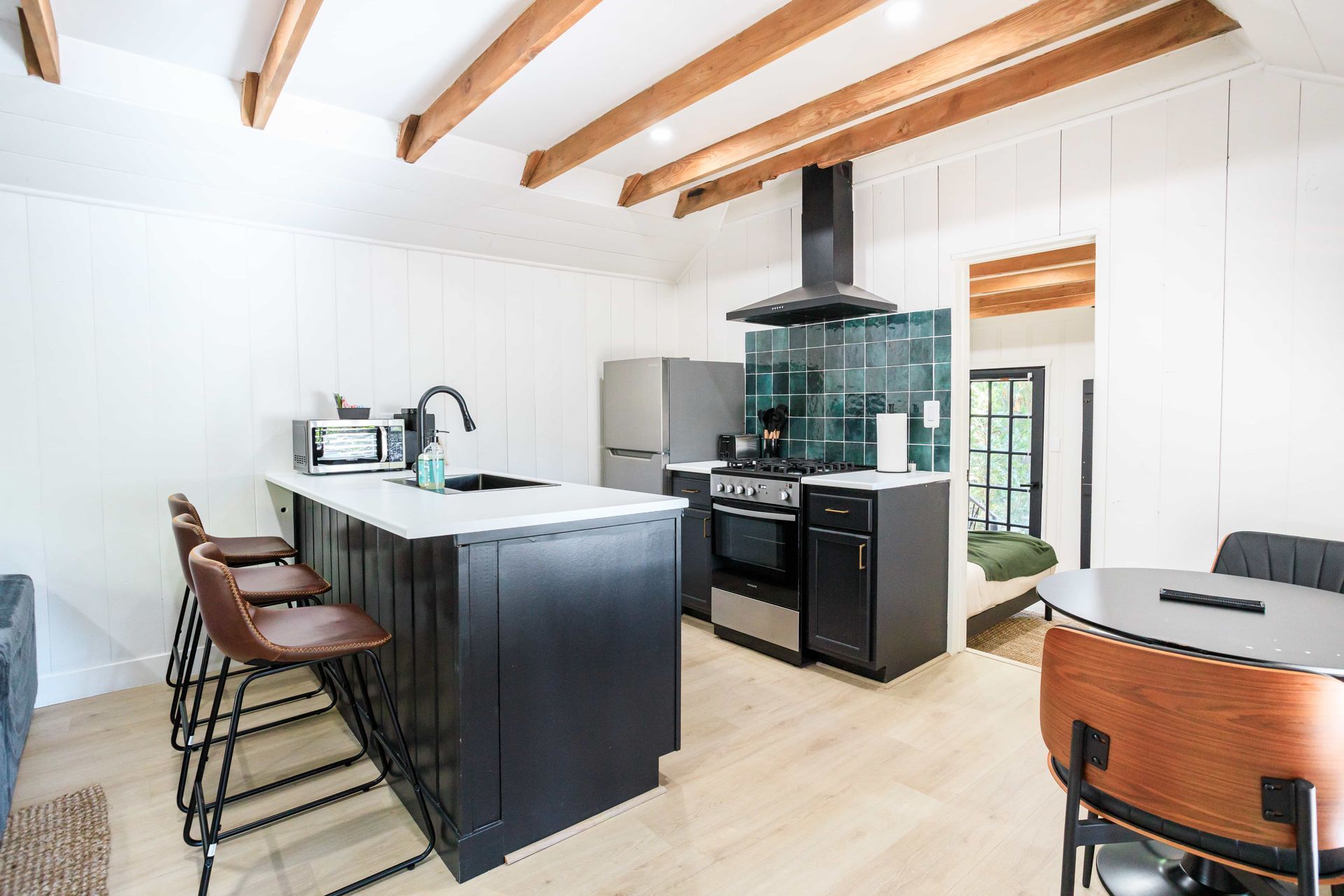 A kitchen with a large island , stove , refrigerator , table and chairs.