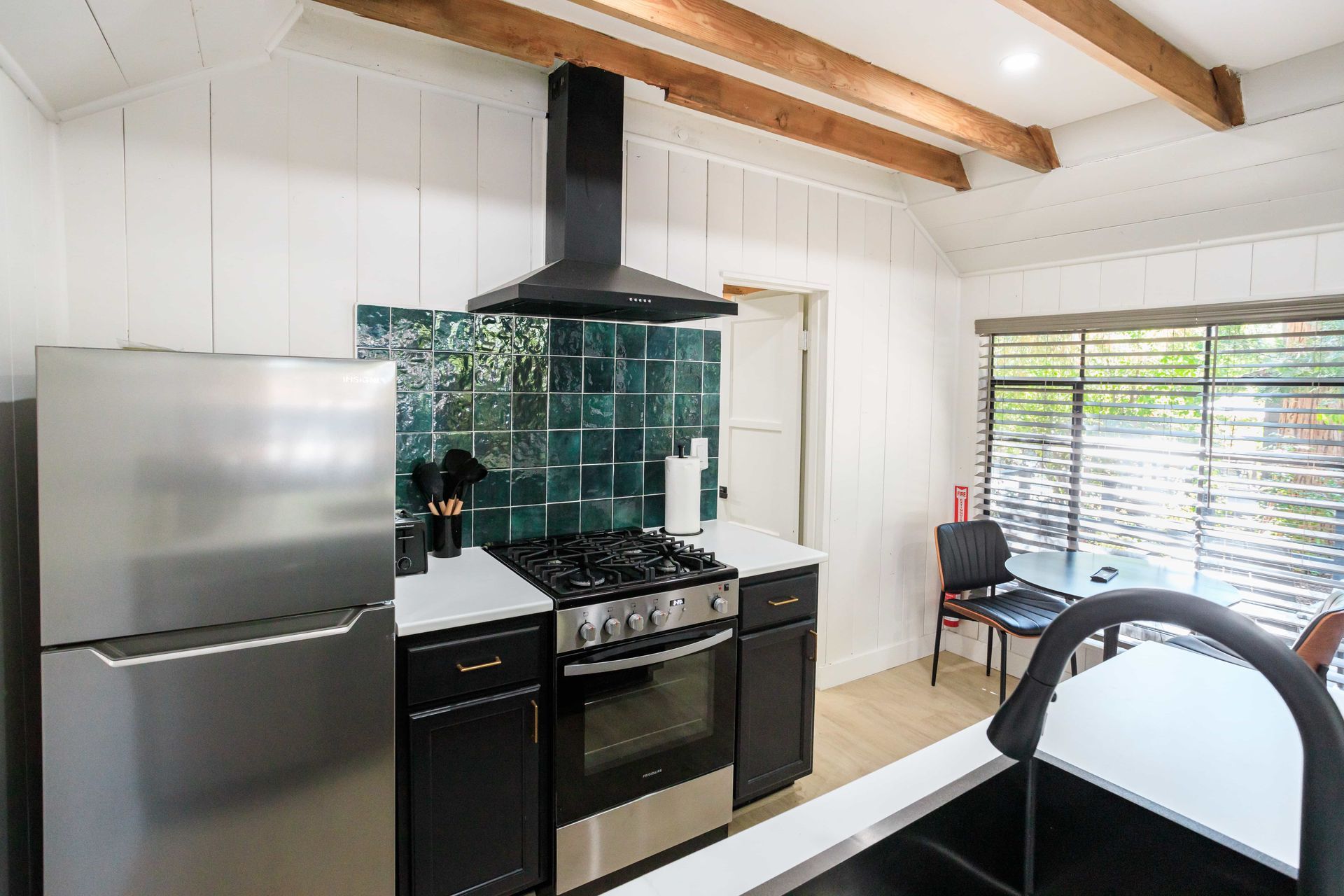 A kitchen with a stove , refrigerator , and sink.