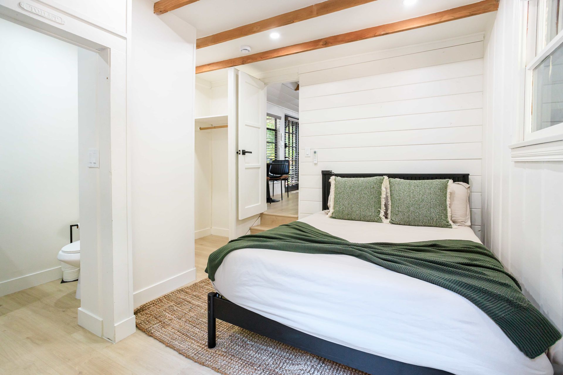 A bedroom with a bed and a bathroom in the background.