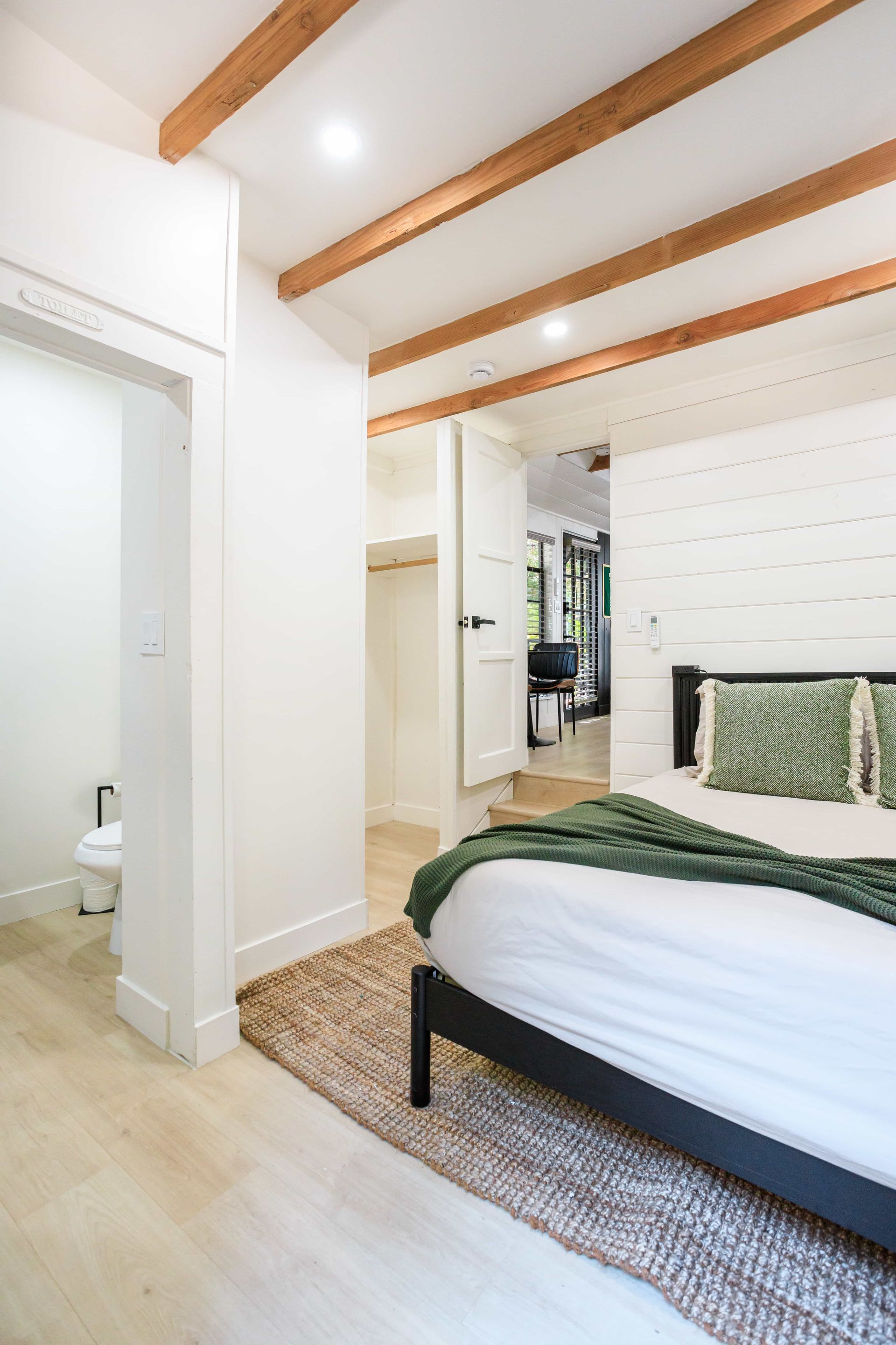 A bedroom with a bed , rug , and wooden beams.