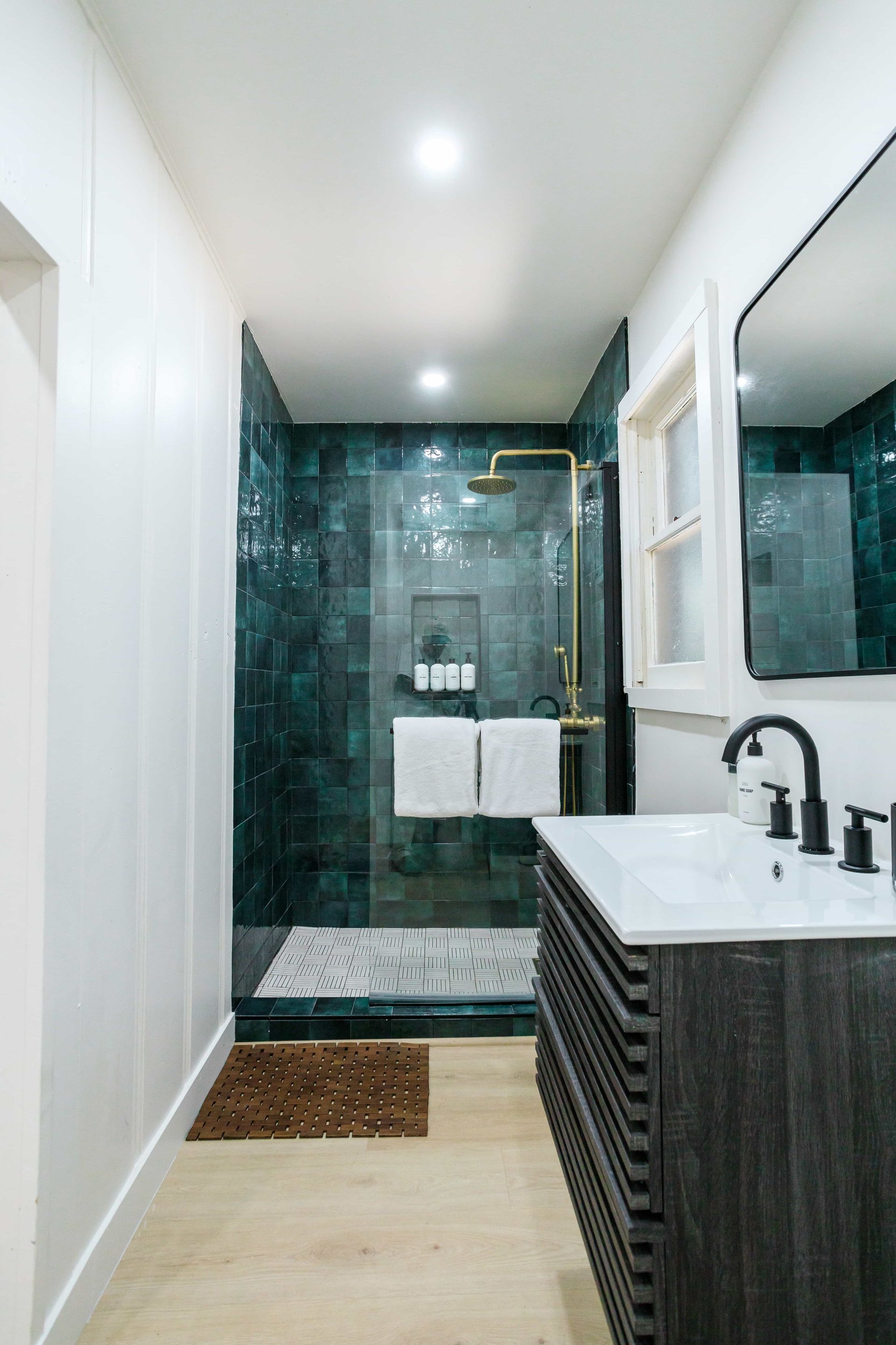 A bathroom with a sink , mirror and walk in shower.