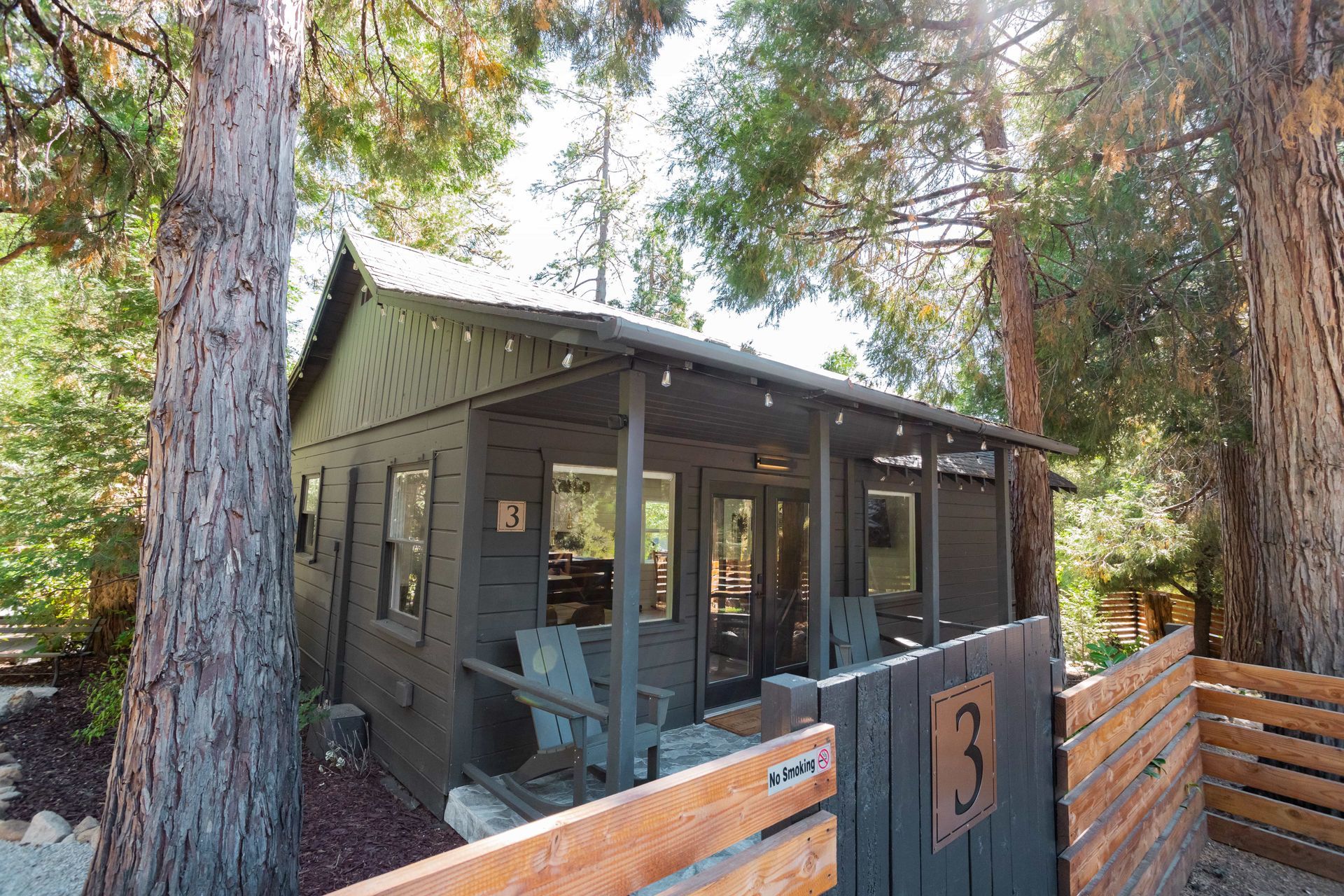 A small house with a porch is surrounded by trees.