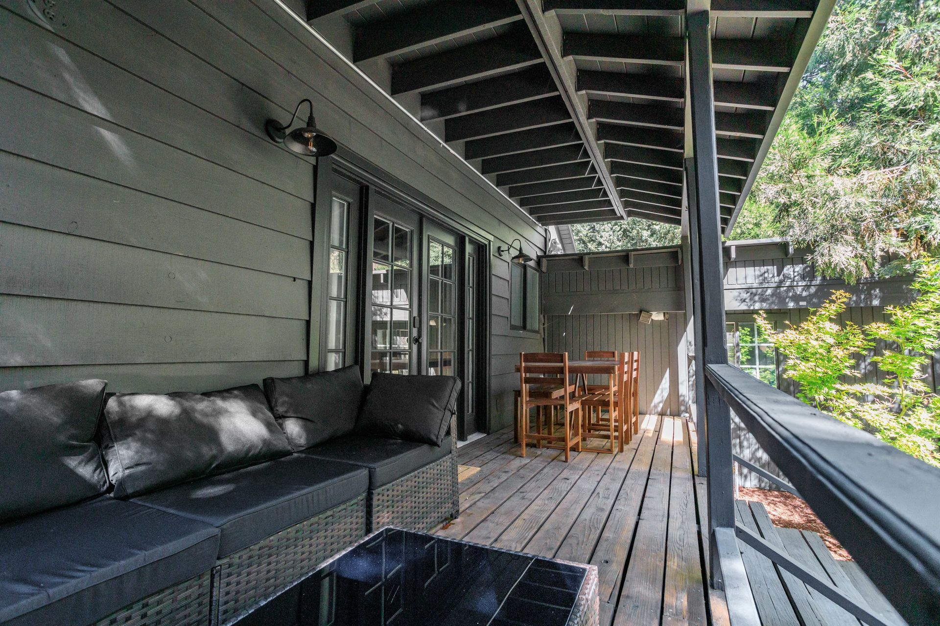A wooden deck with a couch , table and chairs on it.