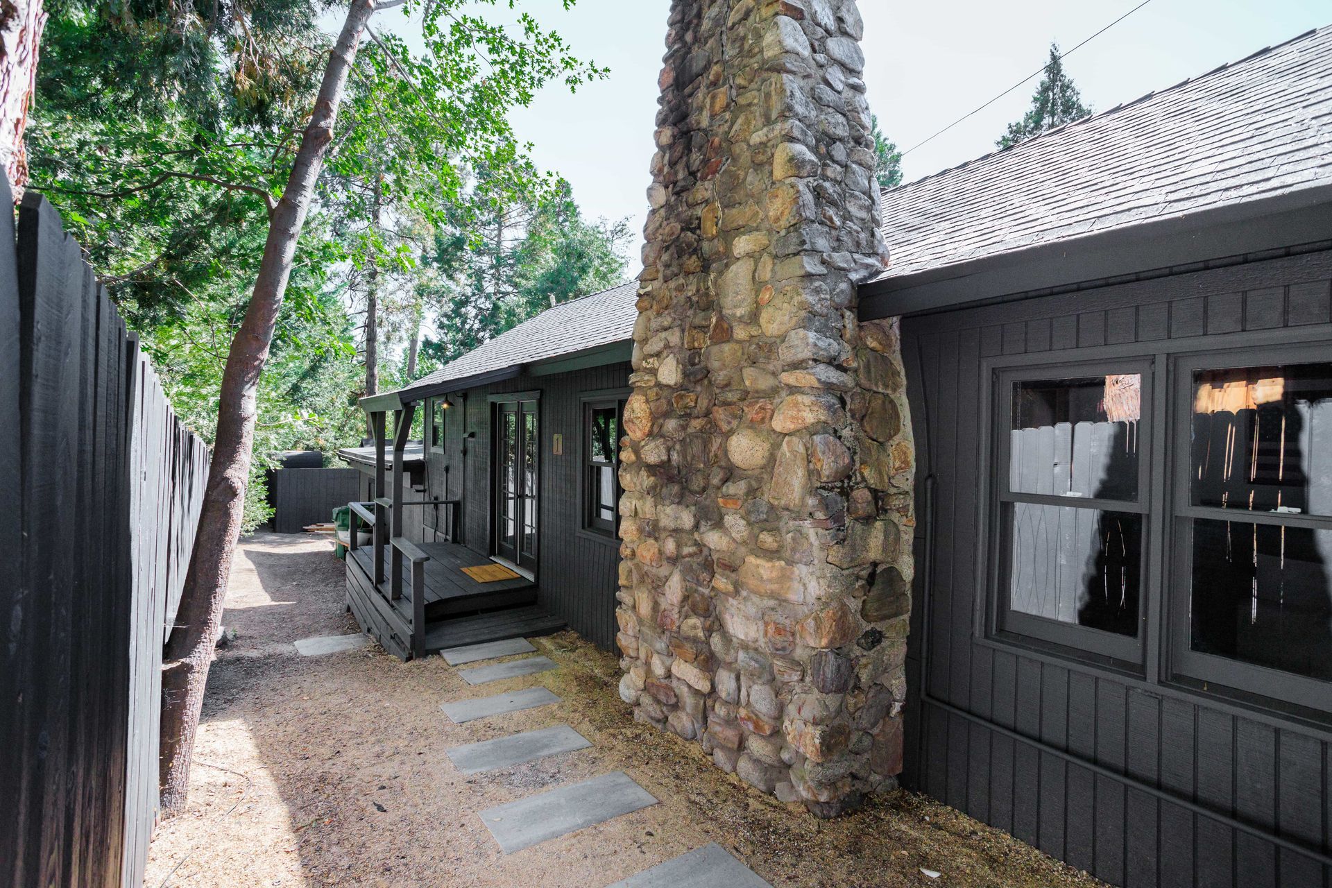 A black house with a stone chimney on the side of it.