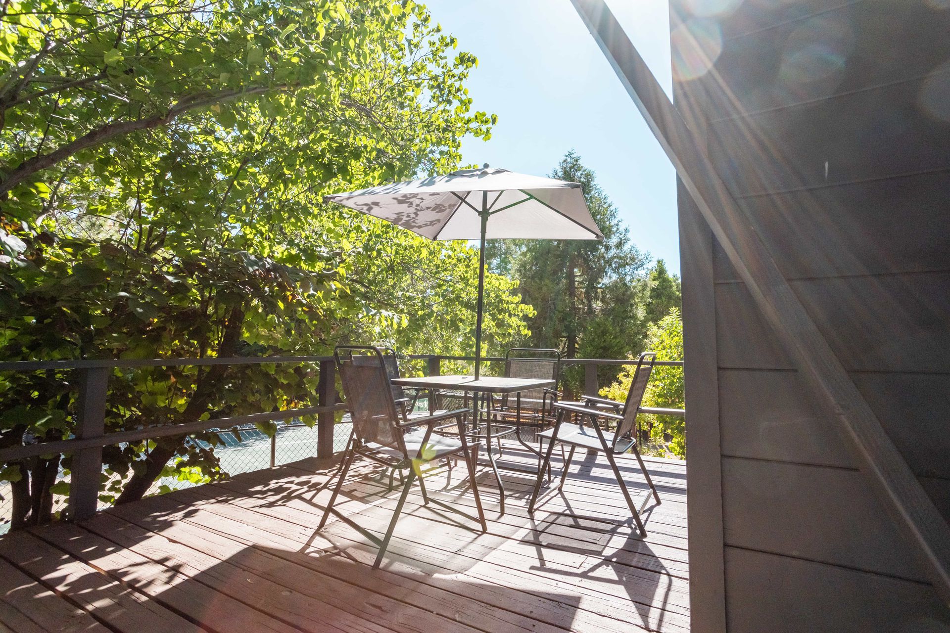 A wooden deck with a table and chairs and an umbrella.