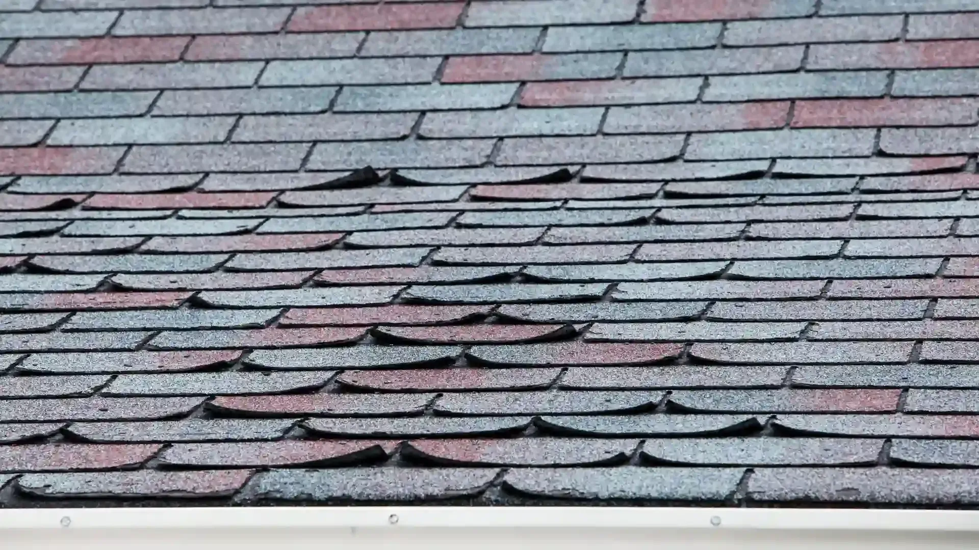 Damaged asphalt shingle roof with curling and missing granules.