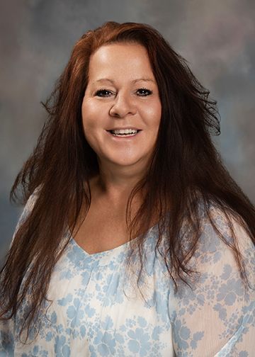 A woman with long hair is smiling for the camera while wearing a blue and white shirt.