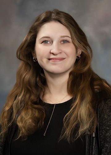 A woman with long brown hair is smiling for the camera.