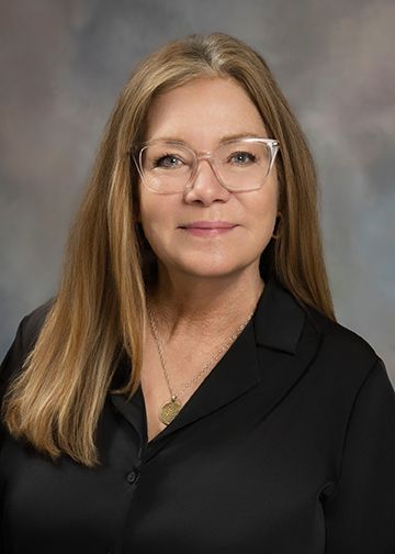A woman wearing glasses and a black shirt is posing for a picture.