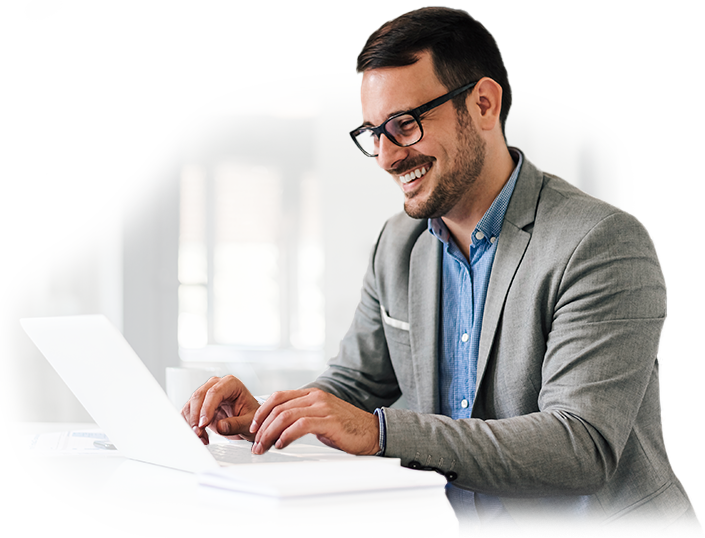 A man in a suit and glasses is typing on a laptop computer.