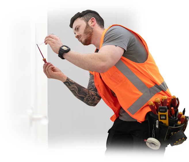 A man in an orange vest is working on a light switch