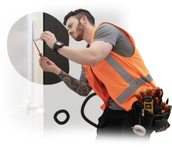 A man in an orange vest is working on a light switch
