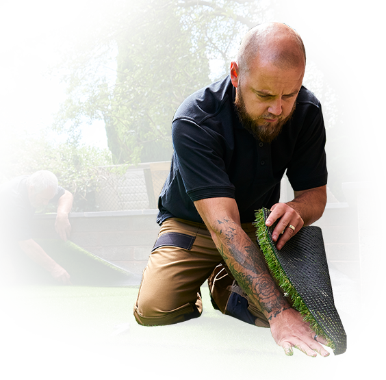 A man is kneeling down and playing with a piece of grass.