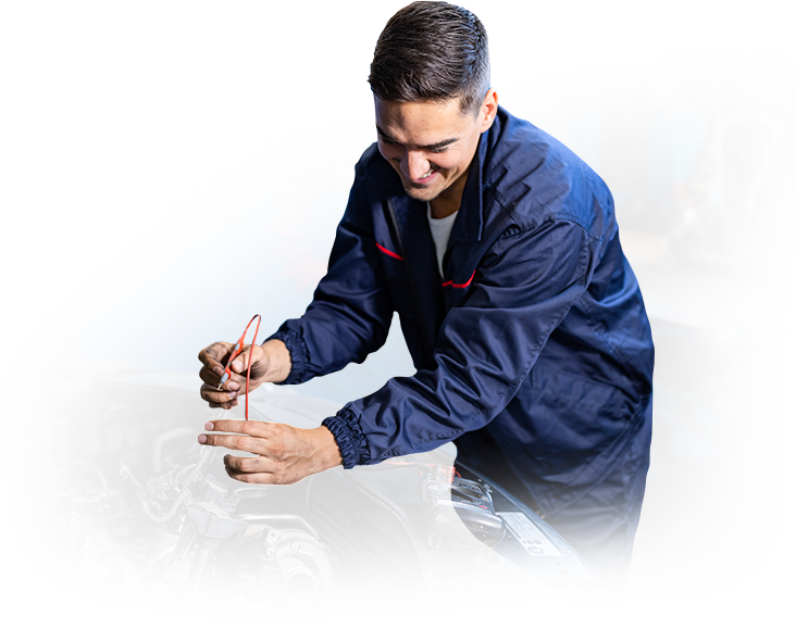 A man in a blue jacket is working on a car engine.