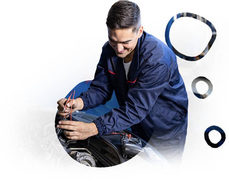 A man in a blue jacket is working on a car engine.