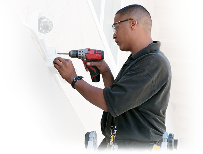 A man is working on a security camera with a drill