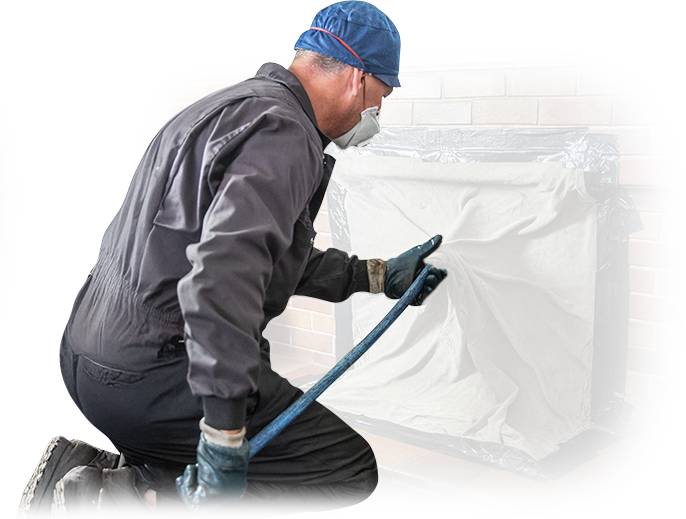 A man wearing a hard hat is working on a brick wall