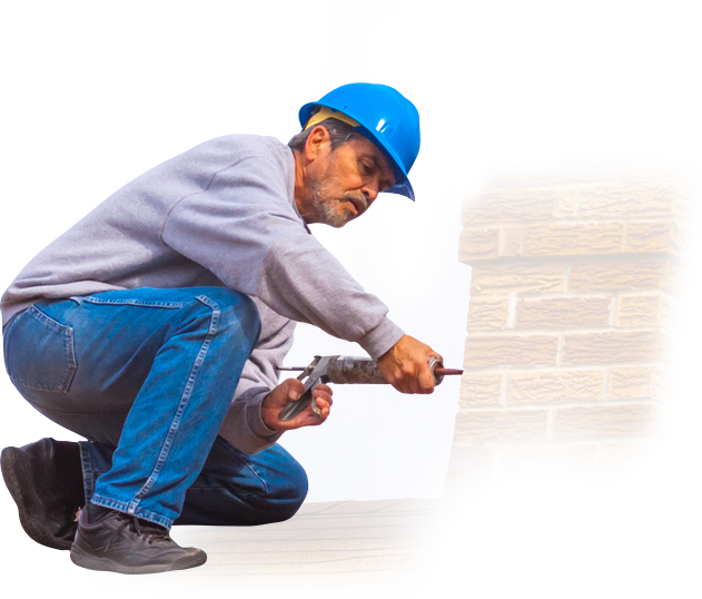 A man wearing a hard hat is working on a brick wall