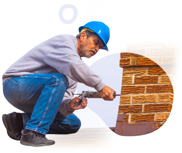 A man wearing a hard hat is working on a brick wall