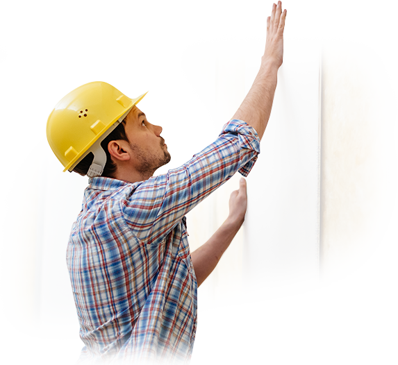 A man wearing a hard hat is working on a wall