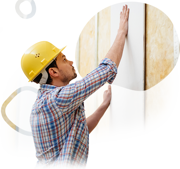 A man wearing a hard hat is working on a wall